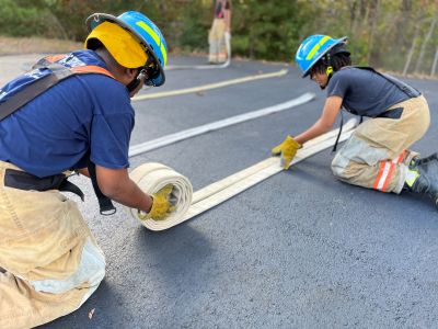Two students rolling up a fire hose